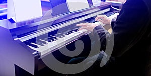 Close-up of a music performer`s hand playing the piano. Side view of instrument musical tool. Close up to the piano keyboard