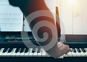 Close-up of a music performer`s man hand playing the piano from back