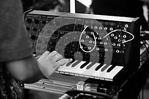 close up of a musician playing analog synthesizer on a black white stage