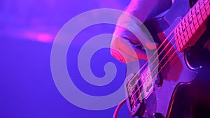 Close-up of musician playing bass guitar during rock concert. World tour of popular musicians