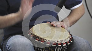 Close up of musician playing djembe drum instrument in home music studio.