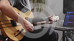 Close up of musician playing electric guitar in home music studio.