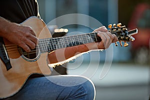 Close up musician playing guitar at garden fete, very colourful blurred background