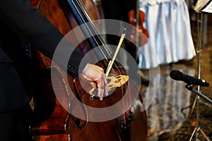 Close up musician`s hand is playing double bass in indoor event