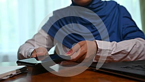 Close-up Muslim woman in hijab plugging in USB cord cable on cell phone, charging or and data transfer on mobile phone
