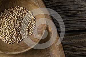 Close up of mustard seeds Rai or brown mustard seeds in a small plate on a wooden background