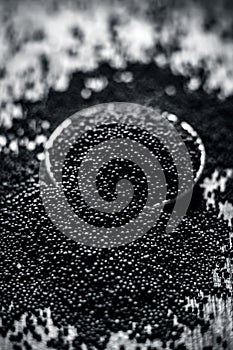 Close up of mustard seeds/Rai or brown mustard seeds in a small plate on a wooden surface in dark Gothic colors.