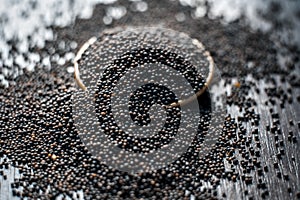 Close up of mustard seeds/Rai or brown mustard seeds in a small plate on a wooden surface in dark Gothic colors.