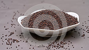 Close up of mustard seeds, Rai or brown mustard seeds in a small white plate