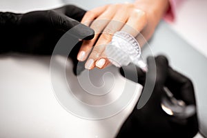 Close up of the nail brush in the hands of professional manicurist