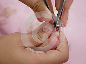 Close up of a nail clippers mother`s hand trimming her baby girl`s toenail