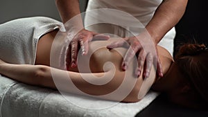 Close-up of naked young woman with perfect skin getting professional relaxing massage at spa salon.