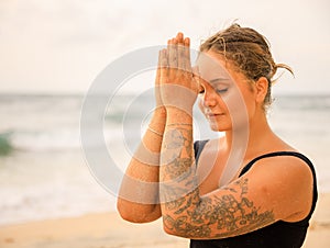 Close up namaste mudra. Attractive Caucasian woman practicing yoga and meditation on the beach. Hands in namaste. Closed eyes.