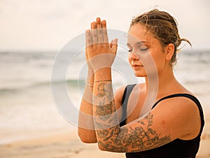 Close up namaste mudra. Attractive Caucasian woman practicing yoga and meditation on the beach. Hands in namaste. Closed eyes.