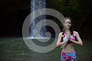 Close up of namaste mudra. Woman meditating, practicing yoga and pranayama with namaste mudra near waterfall. Yoga outdoor concept