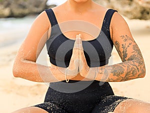 Close up namaste mudra. Yoga at the beach. Woman sitting on sand practicing yoga with namaste mudra. Meditation and concentration