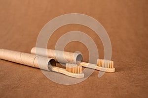 Close up of natural bamboo toothbrushe packed in reusable paper tube on brown kraft paper background with copy space. Sustainable