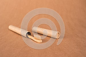 Close up of natural bamboo toothbrushe packed in reusable paper tube on brown kraft paper background with copy space. Sustainable