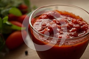 Vista de cerca de tradiciones tomate salsa o una hoja circular grande de masa ligera en vaso un tazón sobre el de madera 