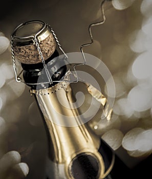 Close-up from nearly opened sparkling wine bottle with sparks on the background.