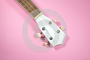 Close up neck of the guitar..White colored wooden ukulele guitar on the pink background. Hawaiian Four String Guitar. Musical