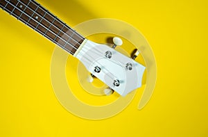 Close up neck of the guitar..White colored wooden ukulele guitar on the yellow background. Hawaiian Four String Guitar. Musical