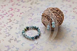 Close-up of a necklace and earrings of green jasper and silver on a background with multi-colored butterflies