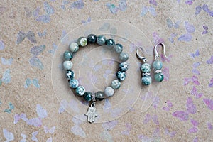 Close-up of a necklace and earrings of green jasper and silver on a background with multi-colored butterflies