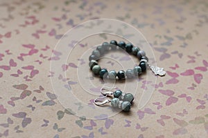 Close-up of a necklace and earrings of green jasper and silver on a background with multi-colored butterflies