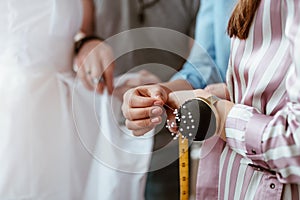 Close-up of needle cushion on tailor`s hand. Taking measurements