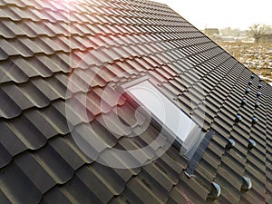 Close-up of new attic plastic window installed in shingled house roof. Professionally done building and construction work, roofing