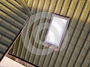 Close-up of new attic plastic window installed in shingled house roof. Professionally done building and construction work, roofing