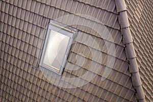 Close-up of new attic plastic window installed in shingled house roof. Professionally done building and construction work, roofing