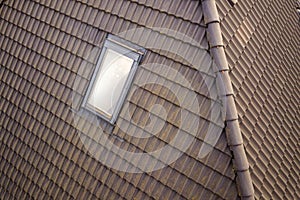 Close-up of new attic plastic window installed in shingled house roof. Professionally done building and construction work, roofing