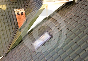 Close-up of new attic plastic window installed in shingled house roof. Professionally done building and construction work, roofing