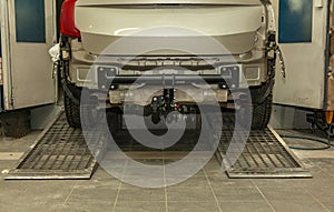 Close-up on a new black tow hitch installed on a modern car with a beige-colored bumper removed in a vehicle repair shop. The