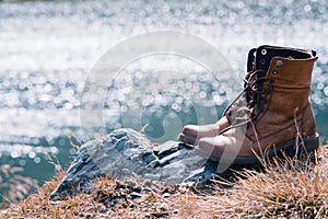 Close up new brown leather shoe on mountain lake view point. Adventure concept, hiker, travel. Copy space