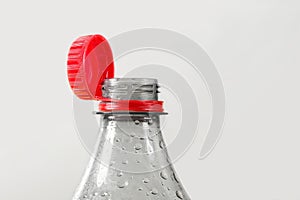 Close up of new cap attached to plastic bottle, isolated on gray background.