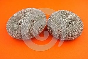 Close-up new metal sponges for washing pans on a bright orange background.Kitchen utensils for washing dishes