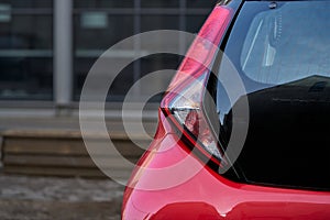 Close up of new red hatchback car parking on local road