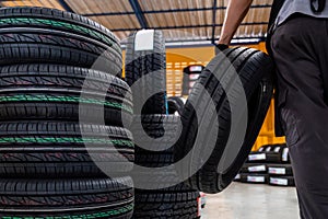 Close-up of New tires, A male auto mechanic storing or stocking new tires at a large warehouse at a service center or auto repair