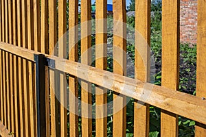 Close-up of a new wooden picket fence in the backyard of a country house, a sunny summer day