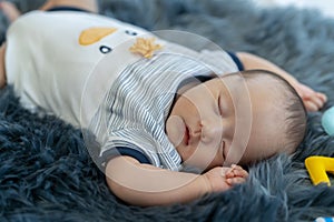 Close Up Newborn, 2 months old, Asian is sleeping on a black-grey carpet with her mother`s hand