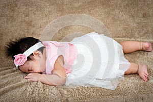 Close-up of a newborn 3 month old Asian woman playing in bed in her home bedroom. after waking up Lie face down on a soft brown