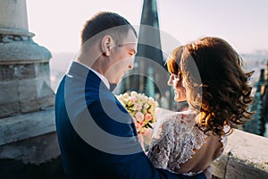 Close-up of newlywed bride and groom hugging on the antique gothic cathedral balcony