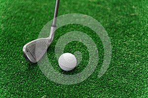 Close-up niblick and white ball for golf on the green grass. Empty right side for text of advert for golf clubs. Playing
