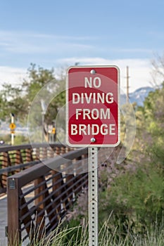 Close up of a No Diving sign beside a bridge with brown metal guardrail