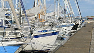 Close-up of noses of sailboats moored by wooden pier in sunny day, yachting in northern Europe