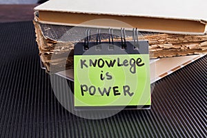 Close-up notebook with knowledge is power quote and old books.