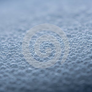 Close-up of numerous small, translucent soap bubbles clustered together. They have a